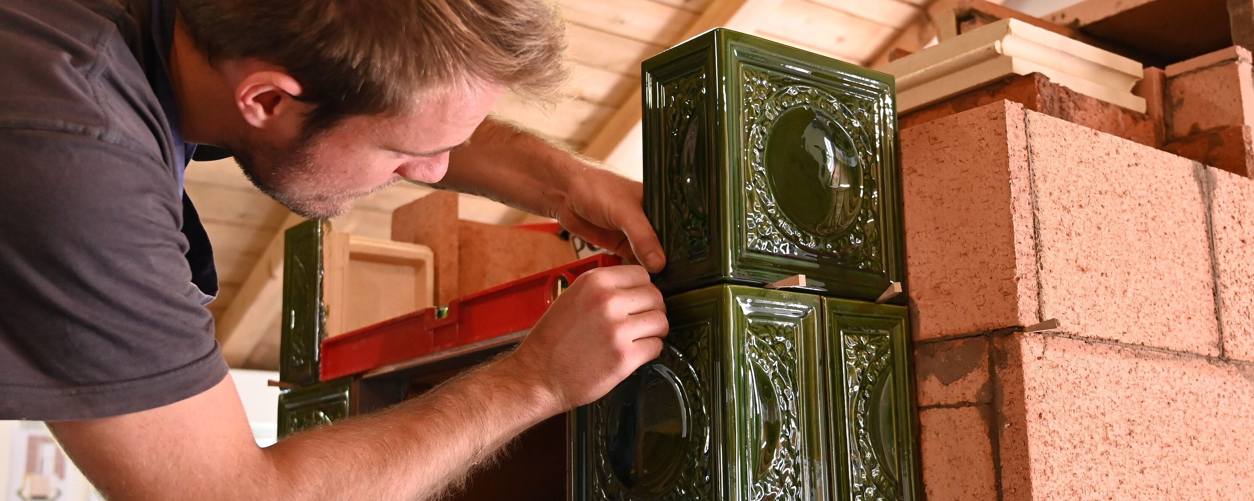 Ein Meister des Ofen- und Luftheizungsbauerhandwerks ist gerade dabei, einen traditionellen Kachelofen zu bauen.