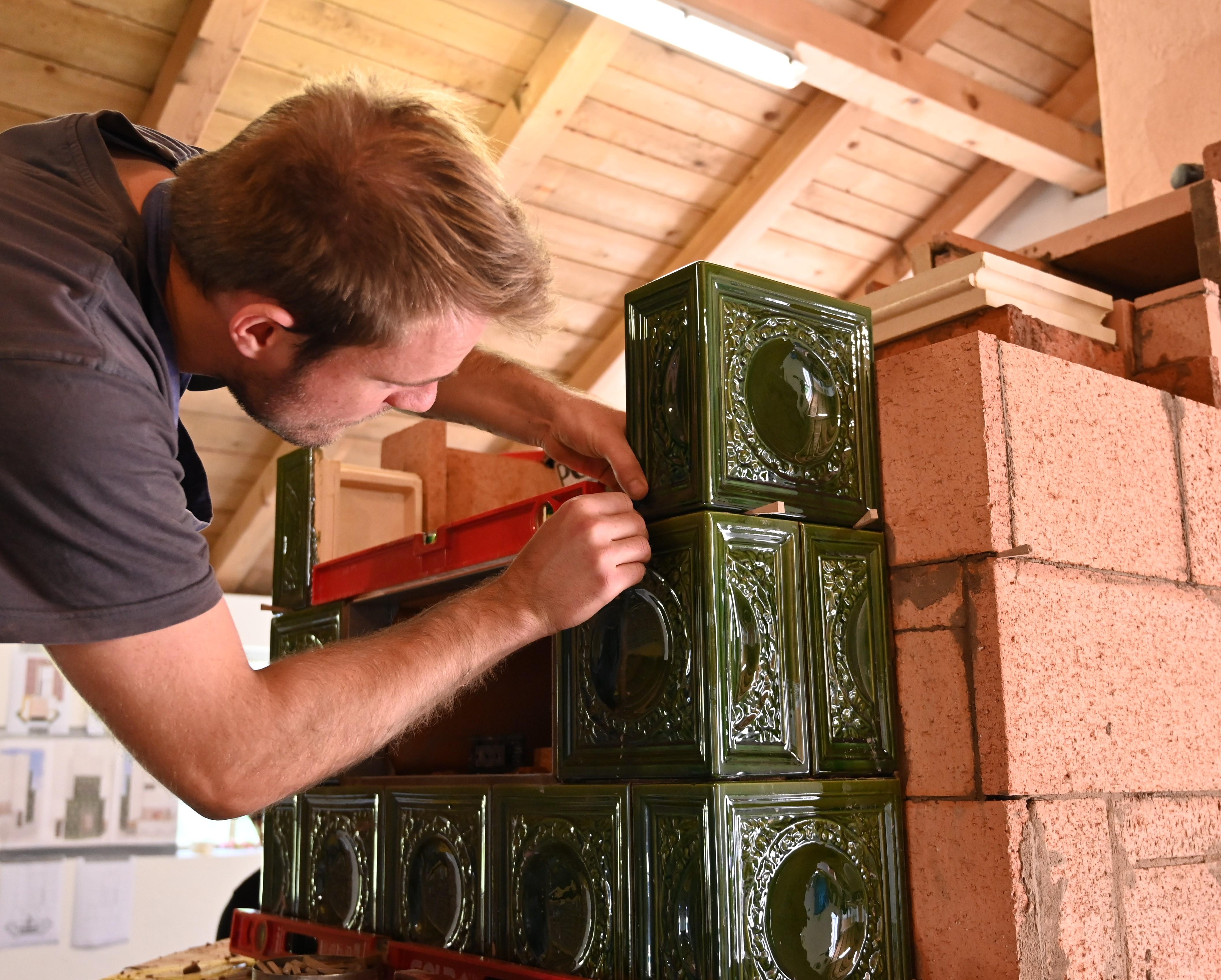 Ein Meister des Ofen- und Luftheizungsbauerhandwerks ist gerade dabei, einen traditionellen Kachelofen zu bauen.